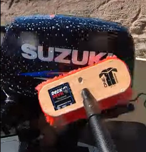 Suzuki outboard motor with a Deck Devil cleaning brush and foamy Ultra Wash soap.